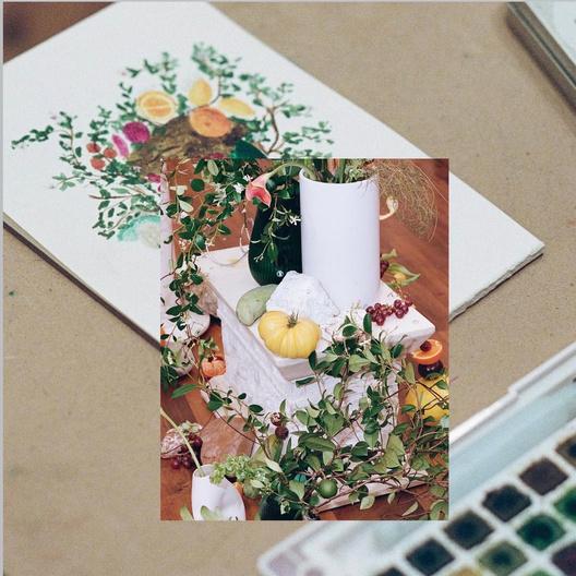 A photograph of a staged still life — a white ceramic jug, a green gourd, a yellow squash, red currants and trailing greenery on a white stone plinth — laid over a second photograph of a loose watercolour of a similar arrangement, painted in greens, citrus yellow and magenta, with a box of watercolour pans beside it.