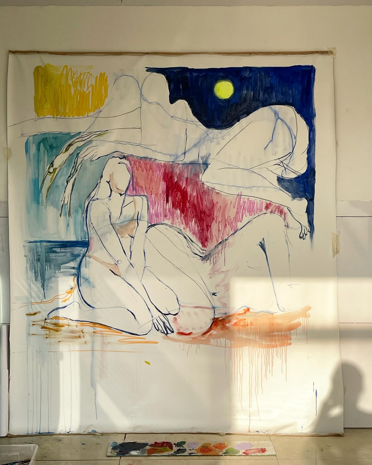 The same painting taped unstretched to a studio wall, the cloth rippling at its edges, a paint-covered board lying on the floor beneath it.